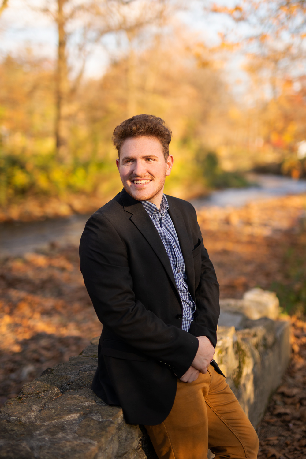 High school senior in a nice dress shirt and jacket leaning against an old stone wall. Photo captured by Dave Zerbe Photography.